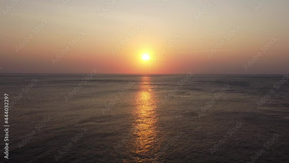 A stunning sunset on the Asian tropical island. Flying over the sea towards a sun.