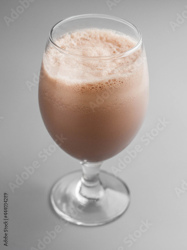 Delicious cold milkshake with chocolate in glass on gray background