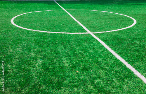The centre of soccer field with artificial green grass and white lines near the school. Amateur football field. Sunny summer day