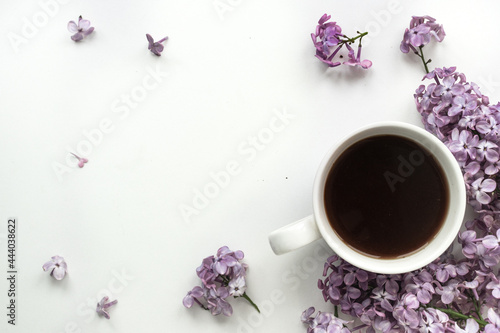 Lilac and cup of coffee in flat style on white wooden background. Beautiful spring. Overhead view. Flat lay, top. Summer season. Natural spring style.