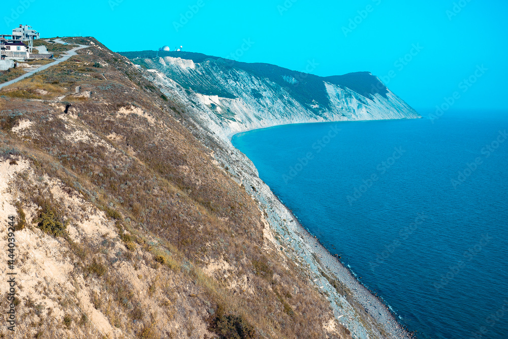 Fototapeta premium Large and beautiful mountains on the sea coast in the sunlight. Beautiful hills on the seashore with yellow grass from heat.