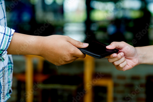 Two men's hands and purse hold the same purse. giving gifts to each other Collecting the wallet and returning it to the owner creating good deeds sharing one's own income © FOTO SALE