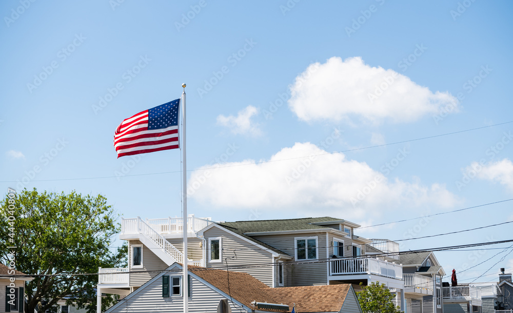 American flag waving in the wind in front of beach houses celebrating the 4th of July, Long Beach Island, NJ, LBI background