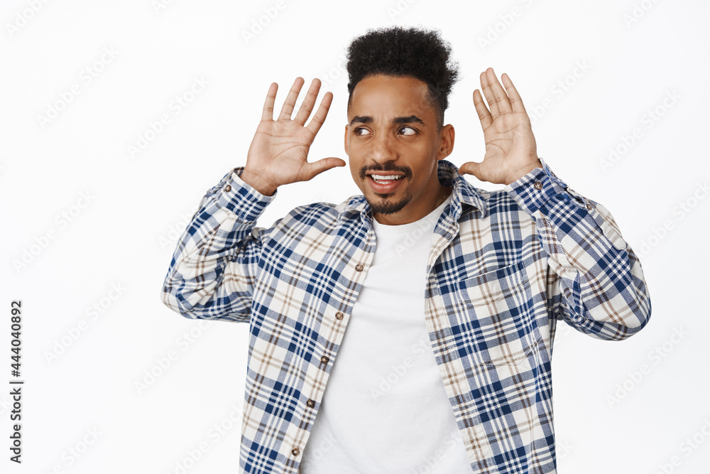 Speak louder, cant hear you. Young african american guy holding hands near ears, looking confused left aside, trying to understand what person saying, white background Speak louder, cant hear you. Young african american guy holding hands near ears, looking confused left aside, trying to understand what person saying, white background