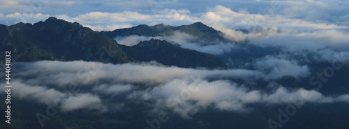 Fog and clouds surrounding green hills and mountains in Entlebuch, Lucerne Canton.