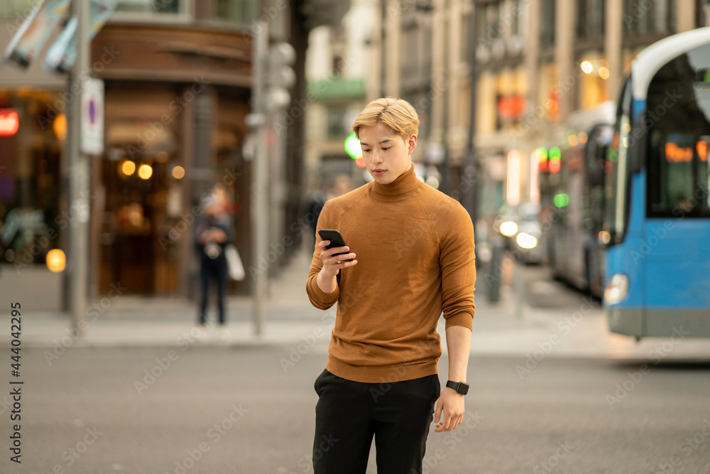 Asian man browsing smartphone in city street Asian man browsing smartphone in city street