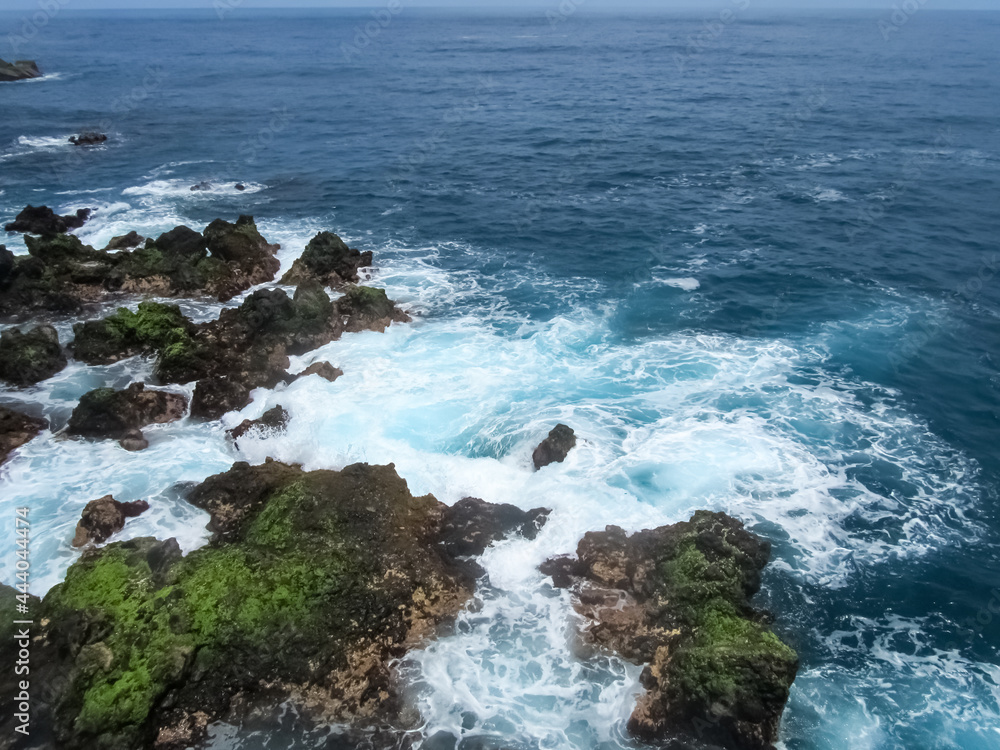 The foamy waves of the ocean surf roll on the rocky shore