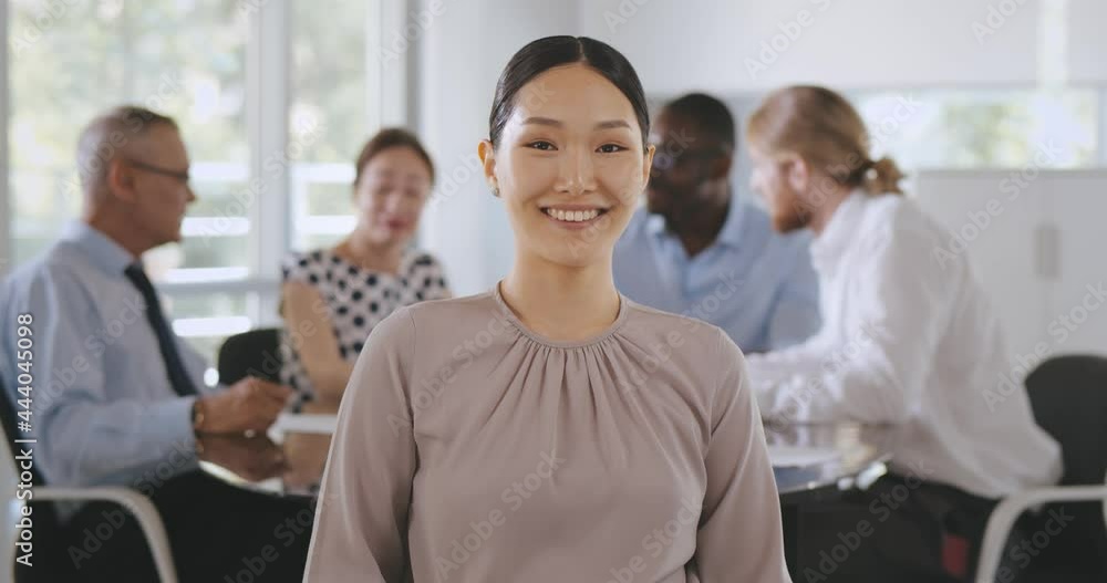Medium shot of asian businesswoman looking at camera sitting at table with colleagues in boardroom Medium shot of asian businesswoman looking at camera sitting at table with colleagues in boardroom