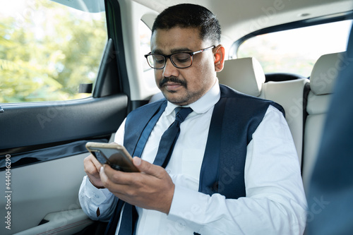 young Businessman busy using mobile phone on moving car - Concept of successful people, technology and happiness. © WESTOCK