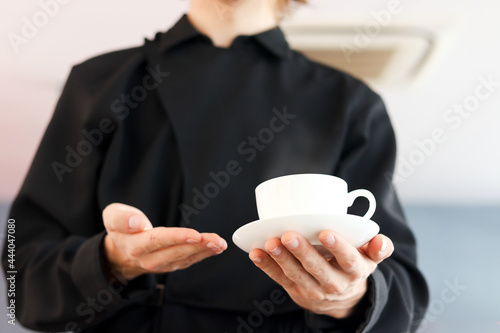 Close up of barista hands holding a cup of hot coffee in the cafe shop,  waiter staff serving coffee to customer in coffee shop counter bar.