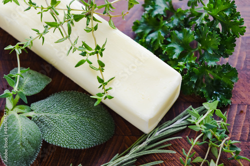 stick of butter surrounded by green herbs photo