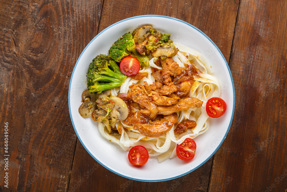 Udon with meat and vegetables in yakiniku sauce in a gray plate on a wooden table. Udon with meat and vegetables in yakiniku sauce in a gray plate on a wooden table.