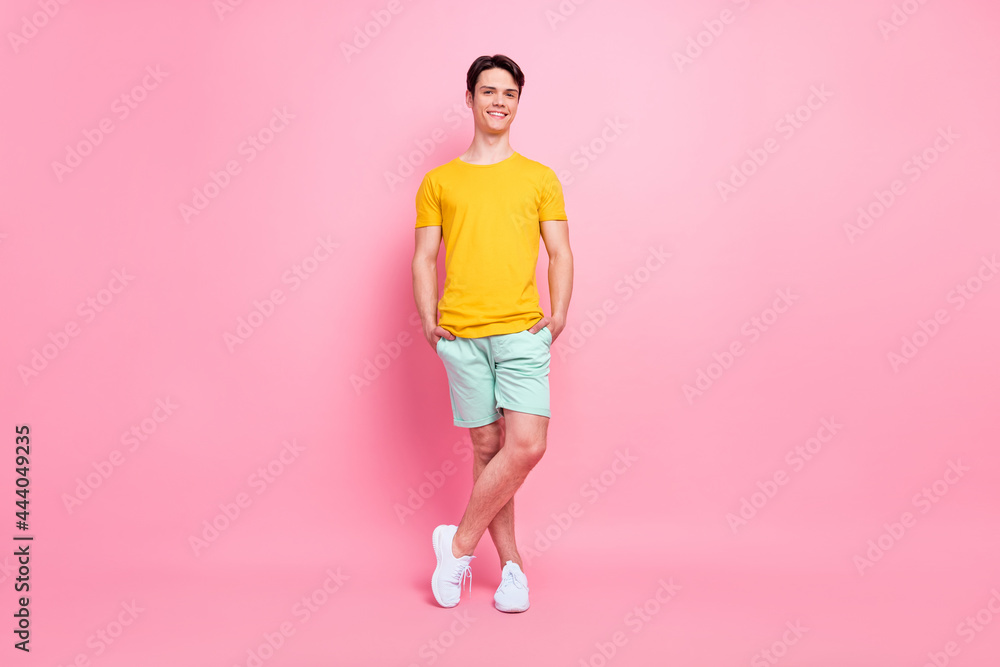 Full length photo of young handsome guy happy positive smile confident hands in pocket summer isolated over pink color background Full length photo of young handsome guy happy positive smile confident hands in pocket summer isolated over pink color background
