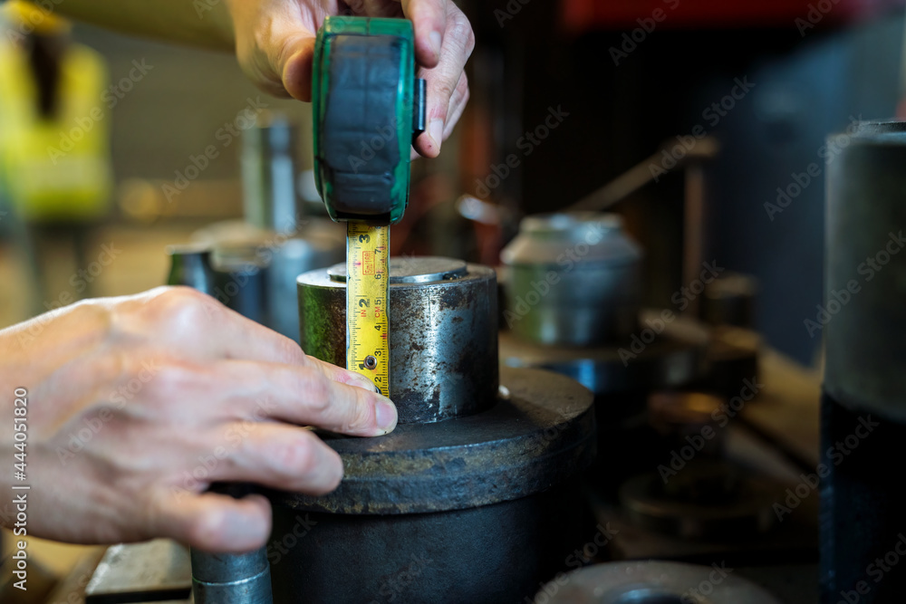 Hand using a steel tape measure. Industrial worker on quality using steel measuring tape measure length a part.