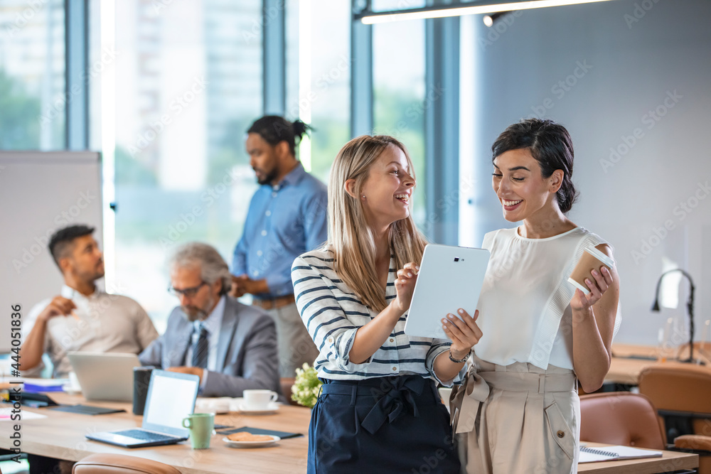 Obraz premium Shot of two businesswomen discussing something on a digital tablet. Business colleagues having a conversation. They are both young business people casually dressed in a modern office.