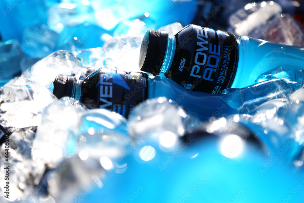 Powerade energy drink. Blue bottle chilling between ice. Drink for athletes. Mountain Blast