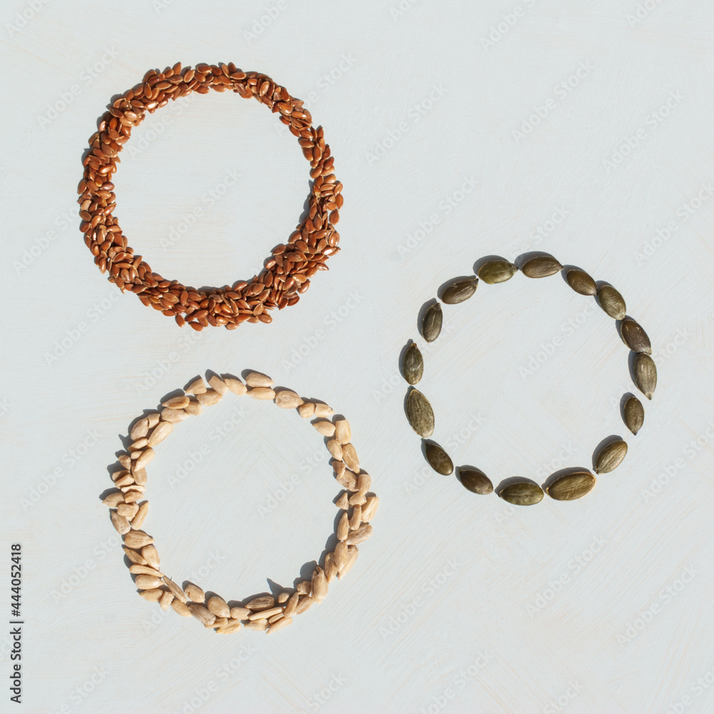 Circles made from different kinds of seeds on white background. Pumpkin seeds, sunflower seeds and linseed. Circles made from different kinds of seeds on white background. Pumpkin seeds, sunflower seeds and linseed.