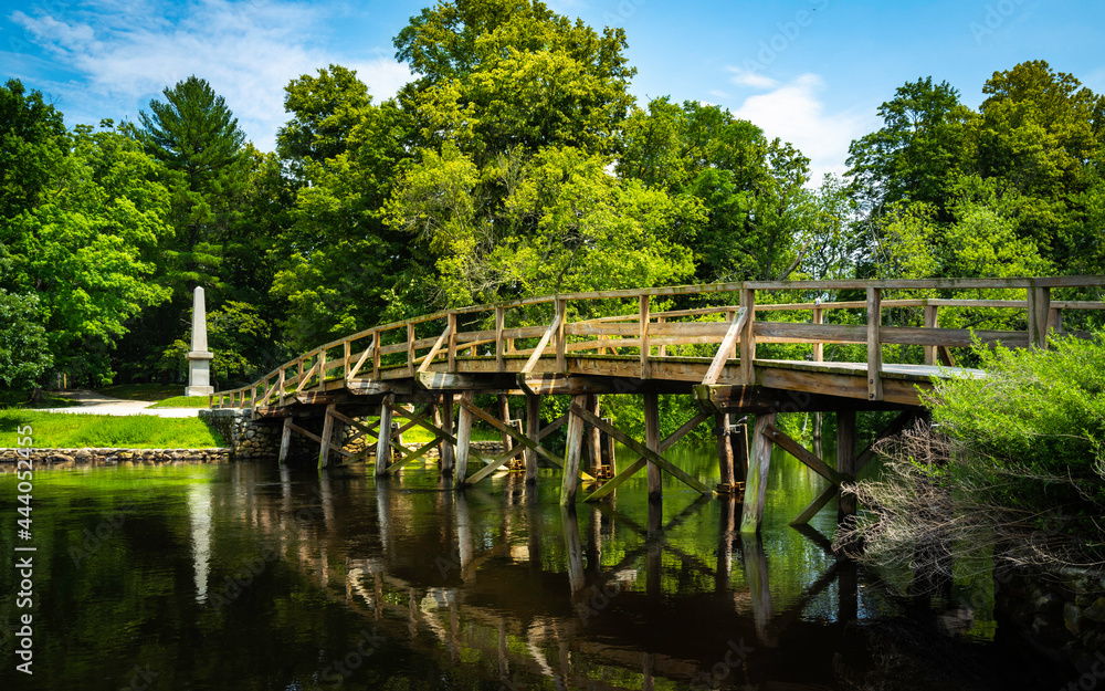 Old North Bridge at Minuteman National Historical Park in Concord, Massachusetts. Tranquil Nature Landscape with Landmark Bridge and Clean River. Peaceful American New England Image. Old North Bridge at Minuteman National Historical Park in Concord, Massachusetts. Tranquil Nature Landscape with Landmark Bridge and Clean River. Peaceful American New England Image.