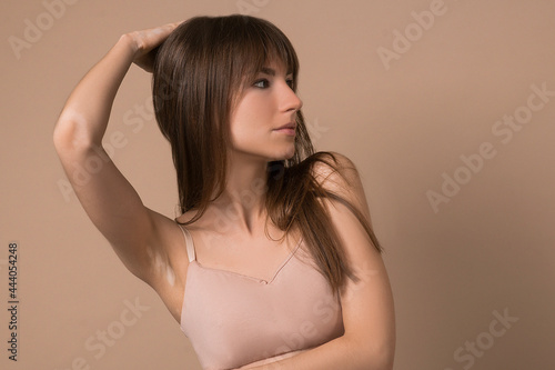 A slim long-haired woman in beige lingerie looking aside photo