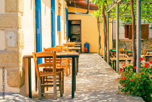 Chairs and tables in an outdoor cafe on a narrow street in Foini, Cyprus. Nobody.