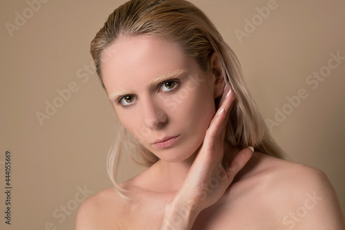 A waist up picture of a blonde young woman with her hands near face photo