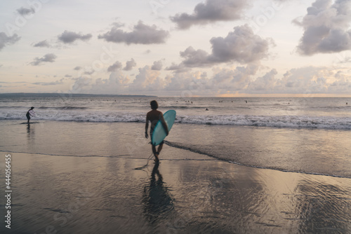 Unrecognizable surfer walking to waving sea across beach