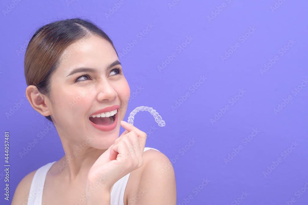 Young smiling woman holding invisalign braces in studio, dental healthcare and Orthodontic concept.. Young smiling woman holding invisalign braces in studio, dental healthcare and Orthodontic concept..