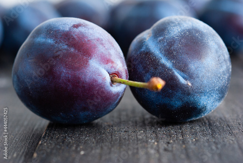 Fotografi plums on black wood table, front view