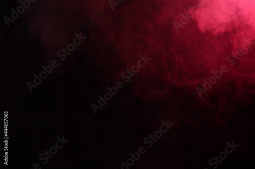 Artificial magic smoke in red light on black background