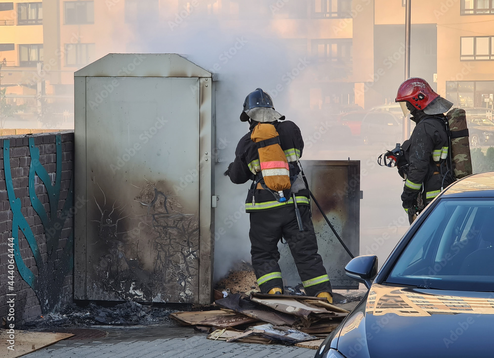 Firefighters extinguishing garbage can fire in car park Firefighters extinguishing garbage can fire in car park