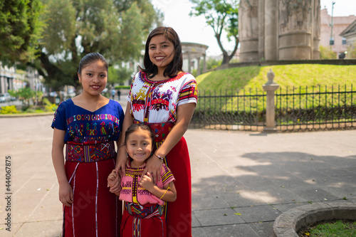 Portrait of two beautiful young women and their little sister wearing a colorful dress from Santa Cruz del Quiche. photo