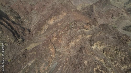 An aerial slow cinematic 4k video over the Hajar Mountains in the UAE showing red and brown rugged mountains  photo