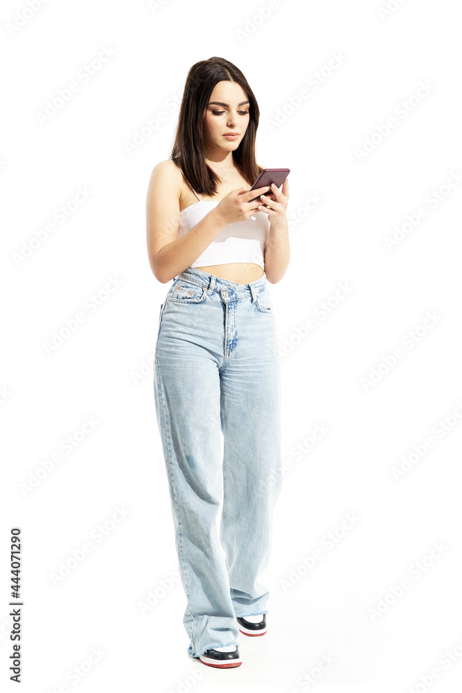 Calm relaxed young trendy gen Z woman using cell phone on sunny bright day. Full body portrait isolated on white background