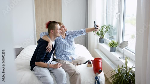 Disabled people taking selfie on bed indoors at home, leg amputee and prosthetic concept. photo