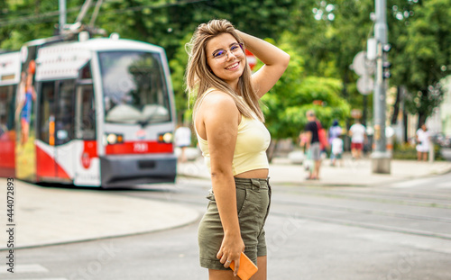 Young girl smiling posing and focusing the camera - Teenager walking in big city in summer outfit holding her smartphone