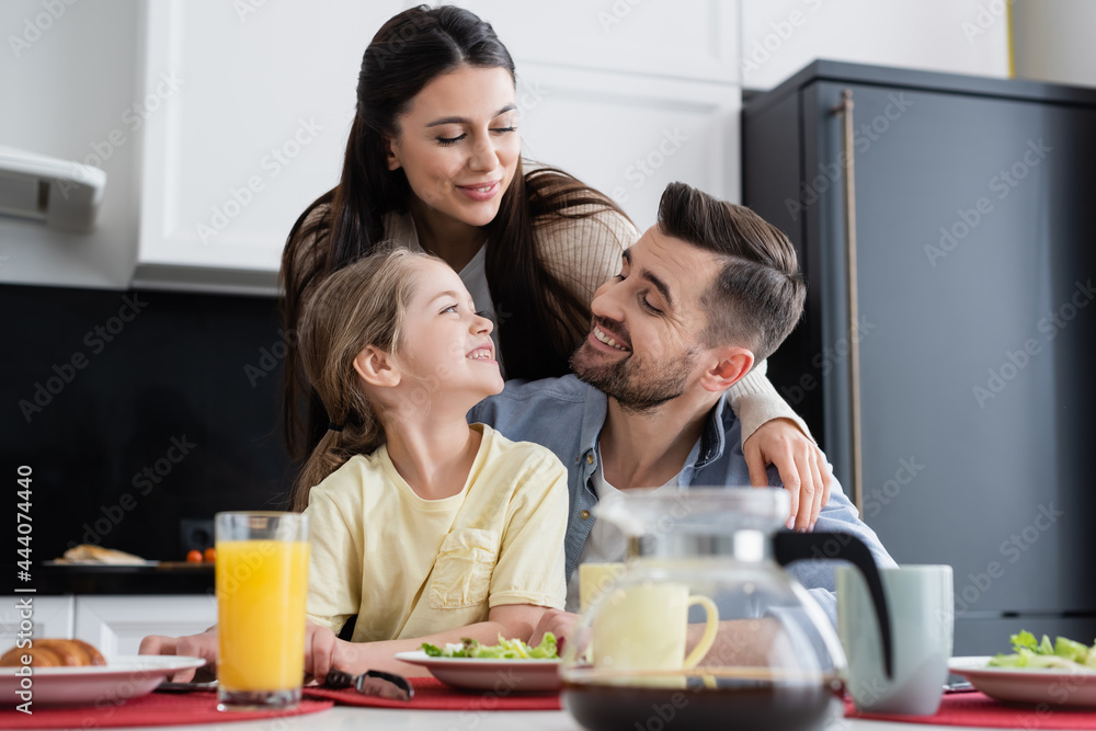 happy family smiling near breakfast in kitchen on blurred foreground happy family smiling near breakfast in kitchen on blurred foreground