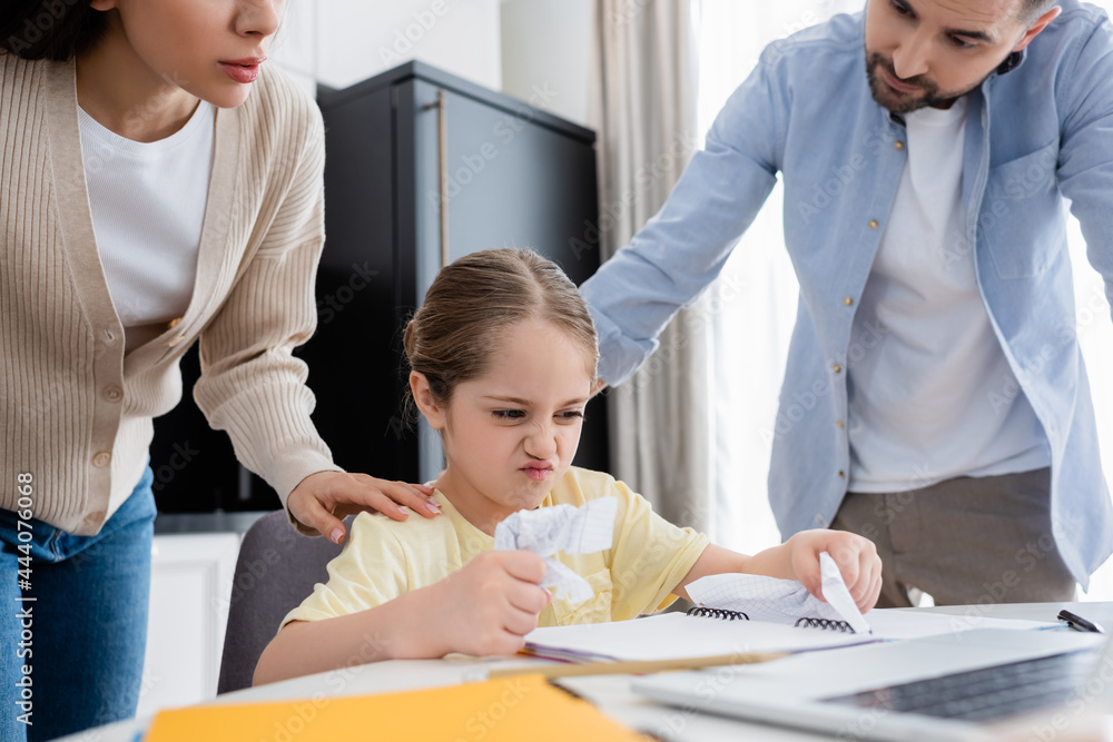 Obraz premium couple calming angry child crumpling paper while doing homework