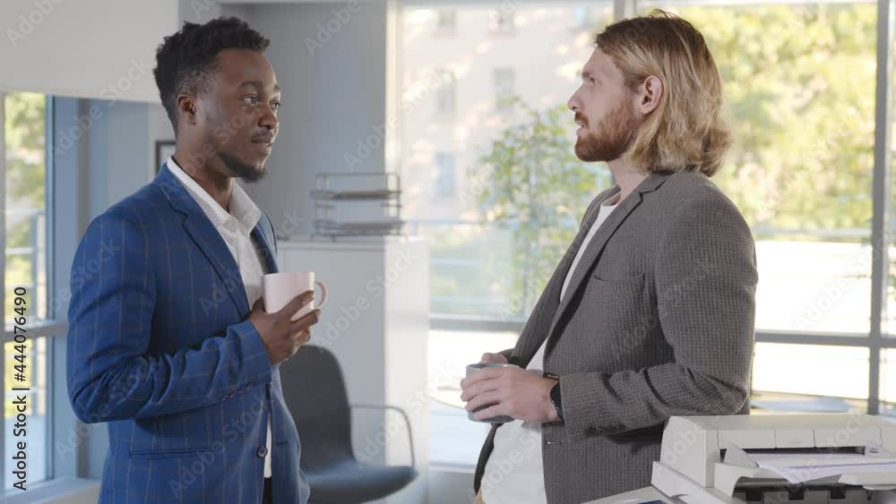 Two young diverse male colleagues drinking coffee in office Two young diverse male colleagues drinking coffee in office