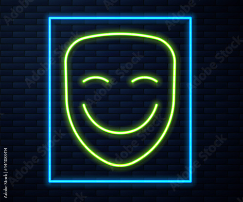 Glowing neon line Comedy theatrical mask icon isolated on brick wall background. Vector