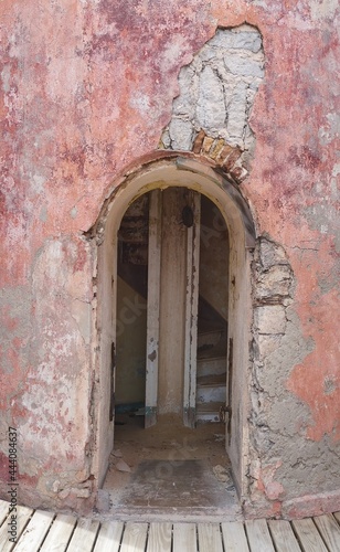 Arched doorway entrance to an old deteriorating building, wall painted in pink