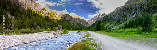 Panoramic view along the river in Valsavarenche  at dusk. Gran Paradiso National Park. View of the river  the mountains  the peaks  the meadows and the woods. Aosta Valley  Italy