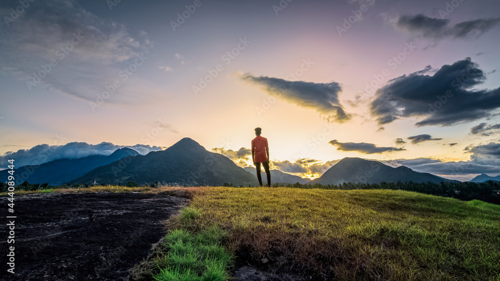 An Adult standing against sunset with Mountain background view near Nagercoil. Kanyakumari District, Tamil Nadu, INDIA. 