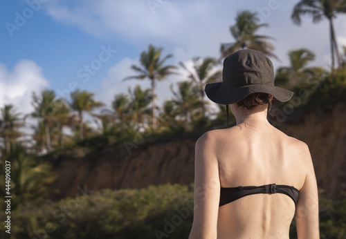 woman in hat and palm trees in the background