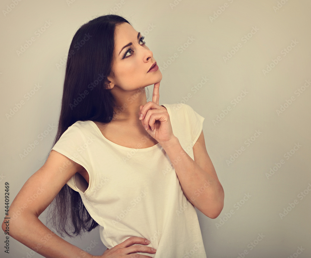 Beautiful serious angry thinking young woman looking up on empty copy space