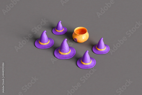 purple witch hats and orange cauldron on dark grey background photo