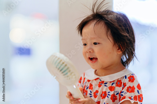 Child blowing a portable fan photo