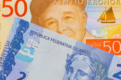A macro image of a gray and orange fifty kronor note from Sweden paired up with a blue two real bank note from Brazil. Shot close up in macro.