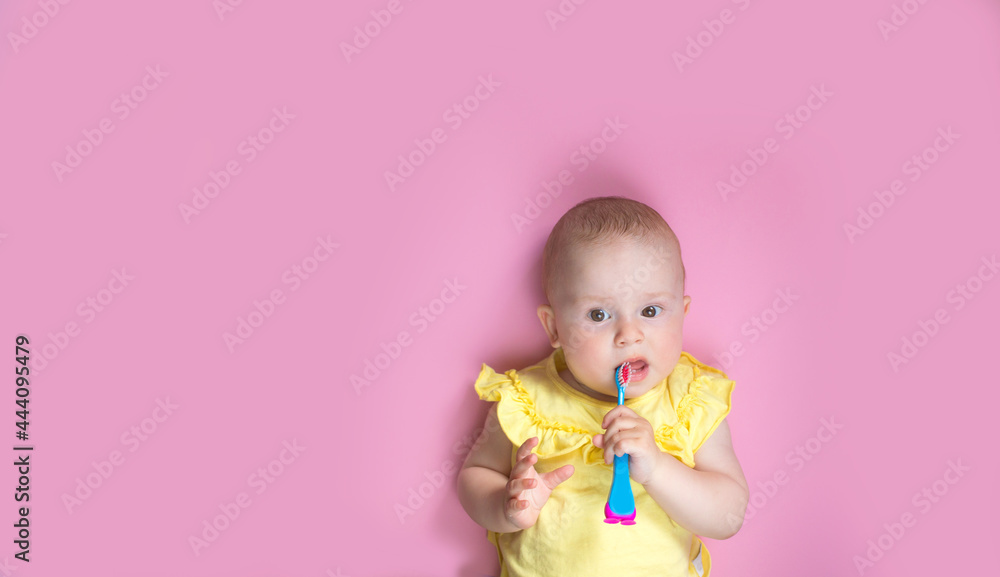 Child on a pink background with a toothbrush brush milk teeth. Prevention of caries in children Child on a pink background with a toothbrush brush milk teeth. Prevention of caries in children