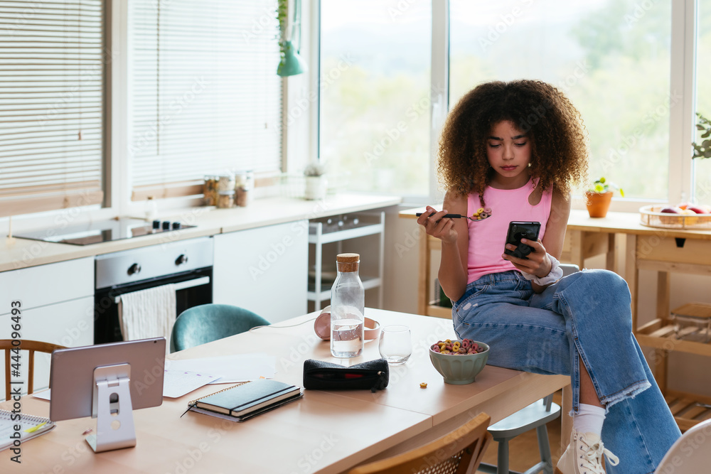 Hispanic girl using smartphone during breakfast Hispanic girl using smartphone during breakfast