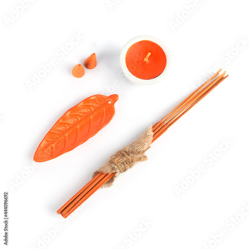 Aromatherapy set burnt orange color on a white background isolated flat lay. Incense sticks, holder, aroma cones, candle close-up, top view. 